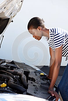 Young black woman on the road trying to fix the broken down car