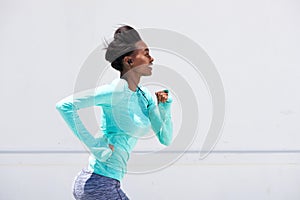 Young black woman running outside with earphones