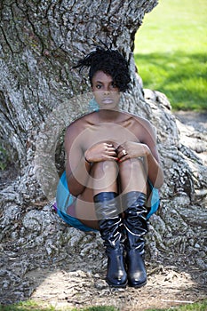 Young black woman sitting at base of tree