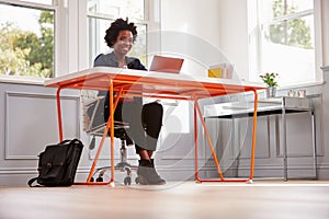 Young black woman sitting at a desk using a laptop computer