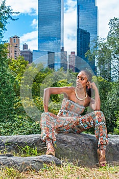 Young black woman sitting outdoors in New York City, relaxing, thinking