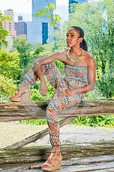 Young black woman sitting outdoors at park in New York City, relaxing