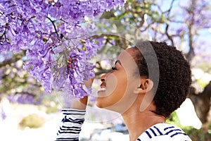 Young black woman smelling flowers on tree