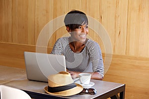 Young black woman smiling and using laptop