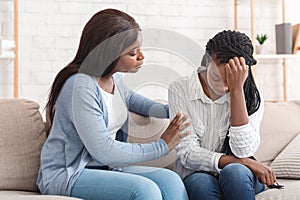 Young black woman supporting her depressed friend at home