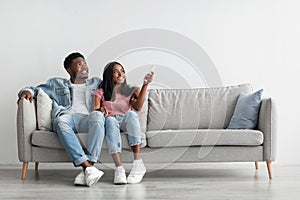 Young black woman switching on air conditioning at her home