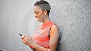 Young black woman texting with her smart phone in urban background.
