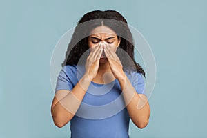 Young black woman touching her nose bridge, suffering from rhinitis, grey background