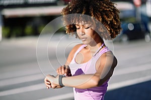 Young black woman using smartwatch touching touchscreen