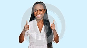 Young black woman wearing casual clothes success sign doing positive gesture with hand, thumbs up smiling and happy