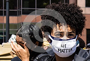 A Young Black Woman Wears a Mask With the Words `We Matter` Written on It