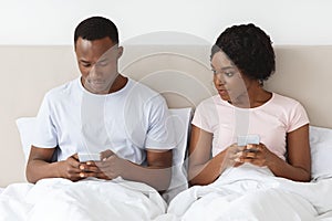 Young black woman eavesdropping on her boyfriend using mobile phone