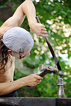 Young blacksmith hammering hot iron