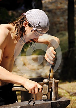 Young blacksmith hammering hot iron