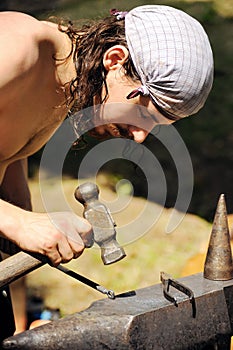 Young blacksmith hammering hot iron