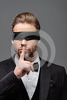 young, blindfolded businessman showing hush sign