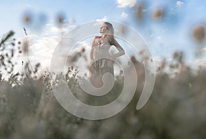 Young blissed woman with in summer field enjoying freedom and summer holidays