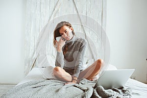 Young blogger or business woman working at home with social media, drinking coffee in early morning in bed