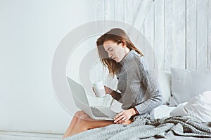 Young blogger or business woman working at home with social media, drinking coffee in early morning in bed