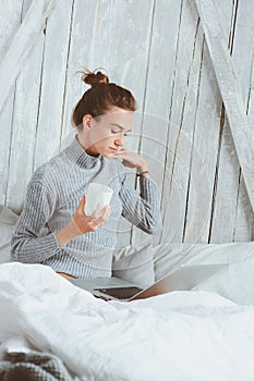 Young blogger or business woman working at home with social media, drinking coffee in early morning in bed