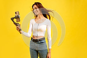 Young blogger girl with three-axis electronic stabilizer gimbal. Makes a selfie and video blog. photo