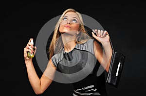 Young blond beautiful woman in dress perfuming herself with bodymist