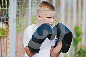 young blond boy in a white t-shirt with boxing gloves