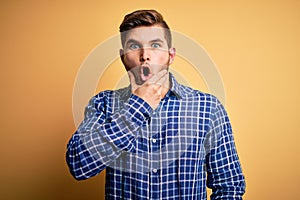 Young blond businessman with beard and blue eyes wearing shirt over yellow background Looking fascinated with disbelief, surprise