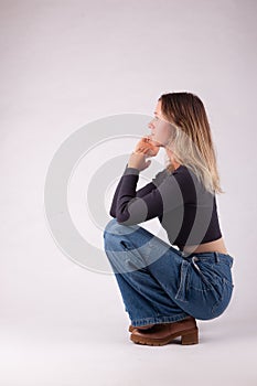 Young blond casual dressed woman crouch jeans