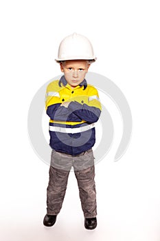 Young blond caucasian boy arms folded role playing as an angry construction worker in a yellow and blue hi-viz shirt and boots