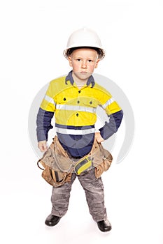 Young blond caucasian boy hand on hip role playing as an angry construction worker in a yellow and blue hi-viz shirt, boots,