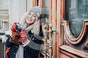Young blond curly female with old film camera, smiling, winter
