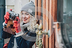 Young blond curly female shooting photo on old film camera