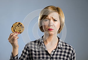 Young blond cute and friendly caucasian woman in casual clothes holding big delicious chocolate cookie