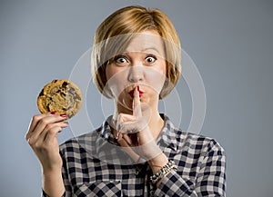 Young blond cute and friendly caucasian woman in casual clothes holding big delicious chocolate cookie