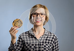 Young blond cute and friendly caucasian woman in casual clothes holding big delicious chocolate cookie