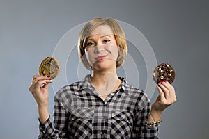 Young blond cute and friendly caucasian woman in casual clothes holding two big chocolate cookies