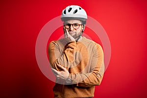 Young blond cyclist man with beard and blue eyes wearing bike helmet and glasses thinking looking tired and bored with depression