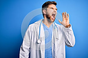 Young blond doctor man with beard and blue eyes wearing white coat and stethoscope shouting and screaming loud to side with hand