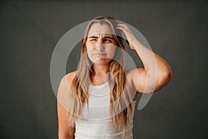 Young blond female scratching her head and thinking