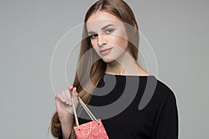 Young blond girl in black holds red gift present package