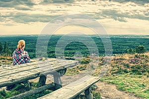 Young blond girl trekker resting at wooden table