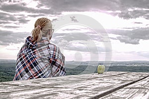 Young blond girl trekker resting at wooden table