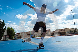 Young blond guy performing skateboarding tricks jumping in the skatepark