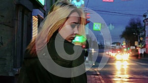 Young blond haired woman in nights street looking back toned shot