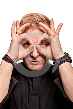 Young blond man in a black shirt, watches and bracelet is making faces, isolated on a white background