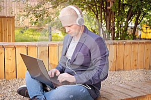Young blond man in a jacket with a laptop.