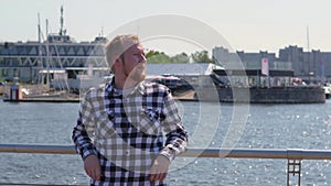 Young blond man walks by the water. Pensive guy is enjoying nature. a man in a checkered shirt walks