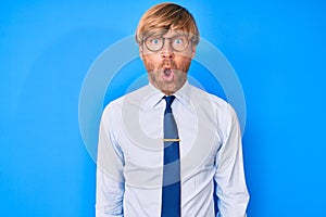 Young blond man wearing business clothes and glasses afraid and shocked with surprise expression, fear and excited face