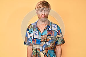 Young blond man wearing summer shirt making fish face with lips, crazy and comical gesture